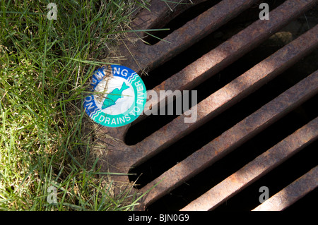 No dumping warning on storm drain to river. Stock Photo