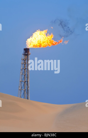 A flare stack burning off excess gas at an oil refinery in the desert Stock Photo