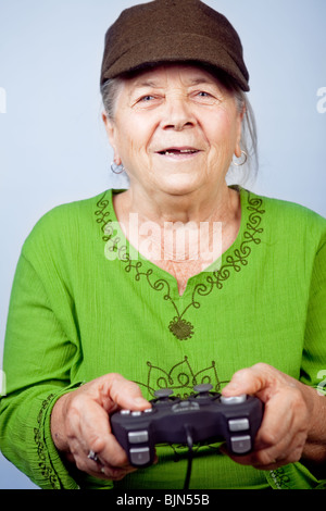 Happy senior woman playing video games with gamepad Stock Photo