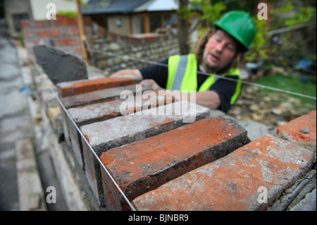 Building of a garden wall with Cotswold stone and reclaimed red bricks UK Stock Photo