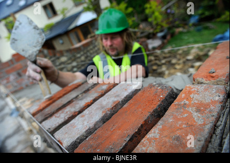 Building of a garden wall with Cotswold stone and reclaimed red bricks UK Stock Photo