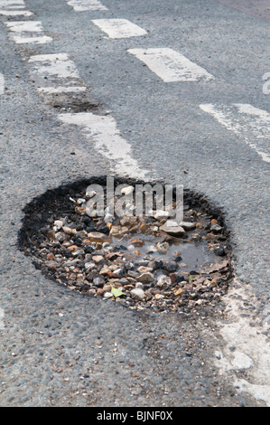 pothole left in road by harsh winter weather Stock Photo