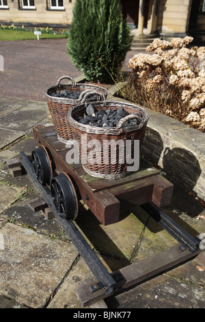 Coal filled baskets on reconstruction of an early railway truck seen at the Durham Miners' Association building, Durham, England, UK Stock Photo