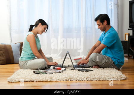Man and woman lying on carpet with laptops Stock Photo