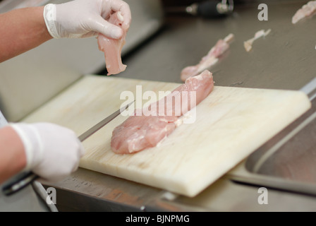 Cutting chicken fillets in a restaurant kitchen Stock Photo