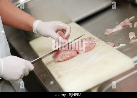 Cutting chicken fillets in a restaurant kitchen Stock Photo