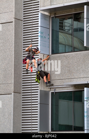 Workers installing sun shade panels on the outside of a highrise building Stock Photo