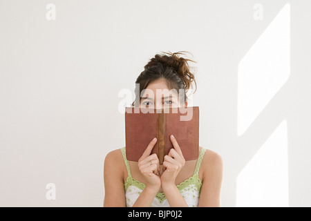 Woman hiding behind a book Stock Photo