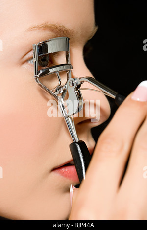 Woman using eyelash curlers Stock Photo