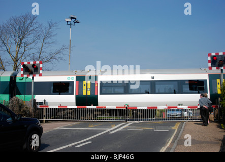 railway level crossing barriers down with a train speeding through Stock Photo