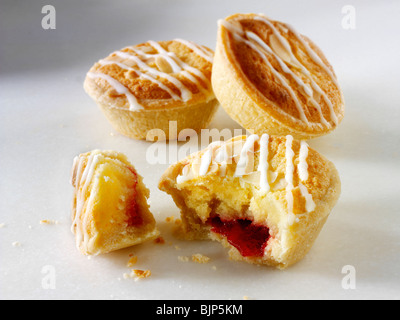 Traditional almond flavoured individual bakewell tarts, on broken open to see filling, on a white background Stock Photo