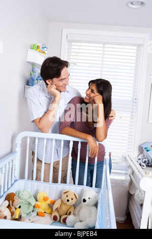 Married couple leaning on baby crib Stock Photo