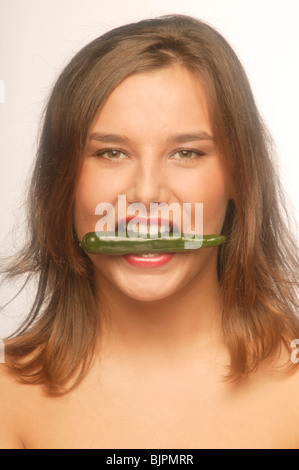 Woman bites into a green pepper Stock Photo