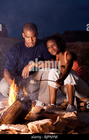 Couple sitting in front of campfire at night Stock Photo