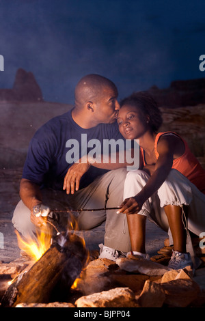 Couple sitting in front of campfire at night Stock Photo