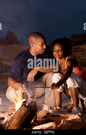 Couple sitting in front of campfire at night Stock Photo