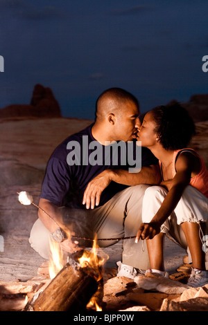 Couple sitting in front of campfire at night Stock Photo