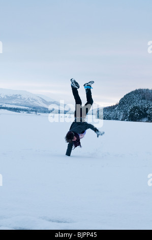 Young man doing a handstand on the ice of frozen Loch Pityoulish Stock Photo