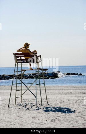 Man sitting in lifeguard chair at beach Stock Photo