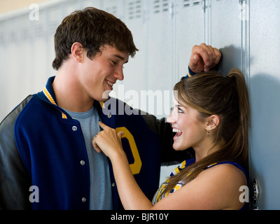 Cheerleader and football player flirting in front of lockers. Stock Photo