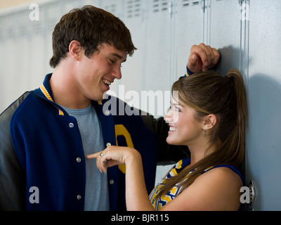 Cheerleader and football player flirting in front of lockers. Stock Photo