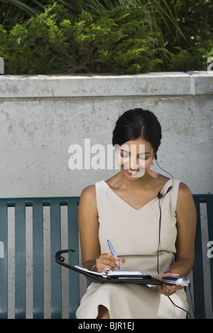 Woman working sitting on a park bench Stock Photo