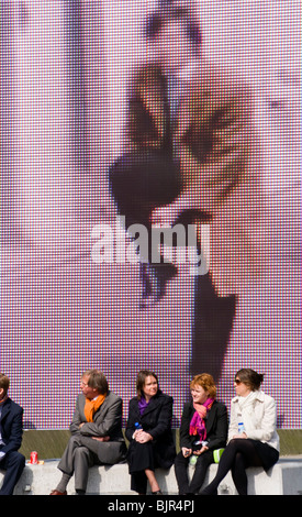 A group of people sitting in front of a large outdoor artwork in Amsterdam Zuid in the Netherlands Stock Photo