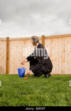 Businessman in front of a fence with a pail and shovel Stock Photo