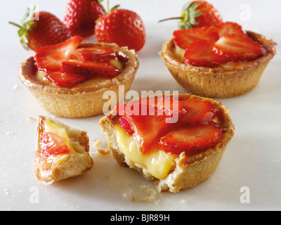 Fresh cooked traditional British strawberry and custard pastry tarts on a white background. Stock Photo