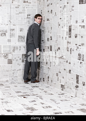 Portrait of young man standing in newspaper room Stock Photo