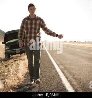 USA, Utah, man hailing on road, broken car in background Stock Photo