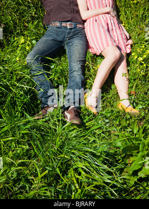 USA, San Francisco, California, young couple lying on grass, low section Stock Photo