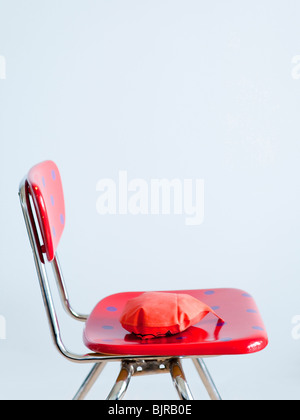 Red whoopie cushion on red spotted chair, studio shot Stock Photo