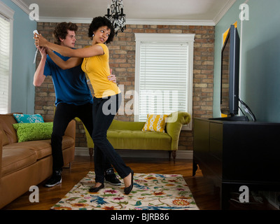 USA, Utah, Provo, young couple holding remote control in living room