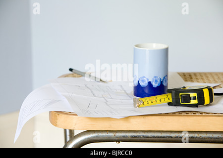 Plans on chair with tape measure and mug Stock Photo