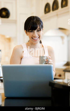 USA, Utah, Alpine, mid adult woman sitting behind laptop and smiling Stock Photo