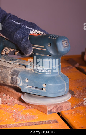 An orbital sander being used to finish a section of timber. Stock Photo
