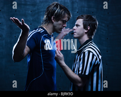 Studio shot of referee showing red card to soccer player Stock Photo