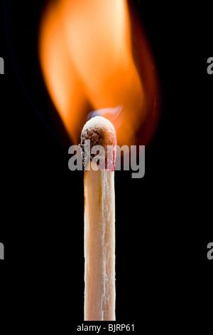 Burning match against black background Stock Photo