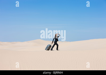 USA, Utah, Little Sahara, businesswoman pulling suitcase in desert Stock Photo