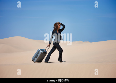 USA, Utah, Little Sahara, businesswoman pulling suitcase in desert Stock Photo