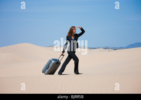 USA, Utah, Little Sahara, businesswoman pulling suitcase in desert Stock Photo