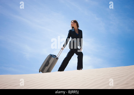 USA, Utah, Little Sahara, businesswoman pulling suitcase in desert Stock Photo