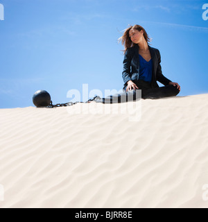 USA, Utah, Little Sahara, businesswoman wearing ball and chain in desert Stock Photo