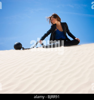 USA, Utah, Little Sahara, businesswoman wearing ball and chain in desert Stock Photo