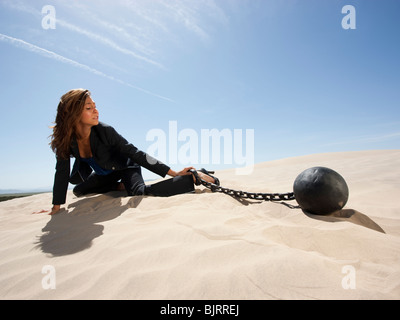 USA, Utah, Little Sahara, young businesswoman pulling ball in chain on desert Stock Photo