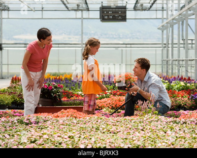 USA, Utah, Salem, girl (8-9) with parents choosing plants in greenhouse Stock Photo