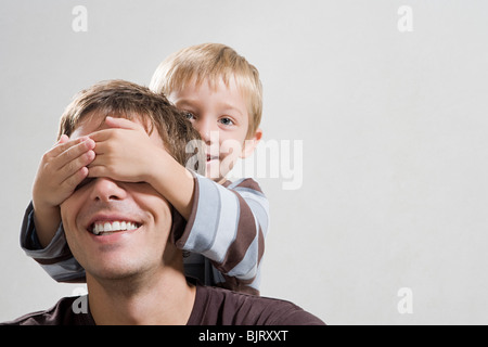 A son covering his fathers eye Stock Photo