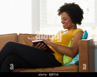USA, Utah, Provo, young woman reading book on couch