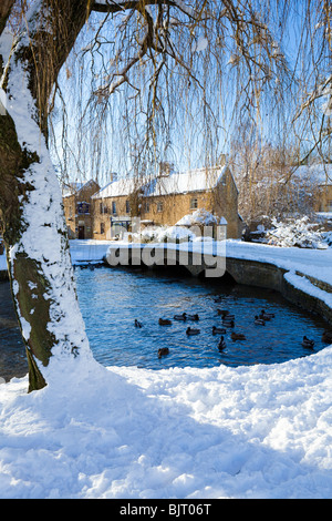 Winter snow on one of the bridges over the River Windrush in the Cotswold village of Bourton on the Water, Gloucestershire UK Stock Photo